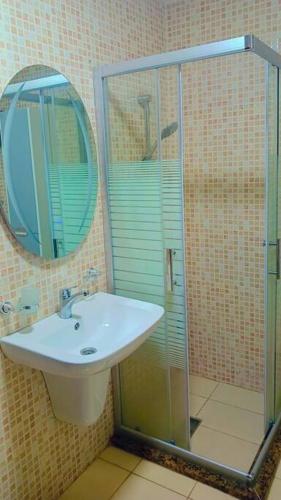 a bathroom with a sink and a shower with a mirror at شقة فاخرة واسعة في شارع المدينة المنورة in Umm Uthainah
