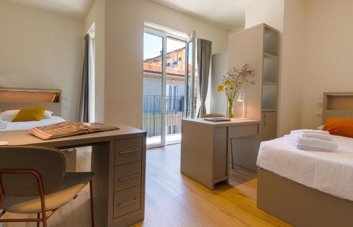 a room with two beds and a desk and a window at S4 Stays in Florence