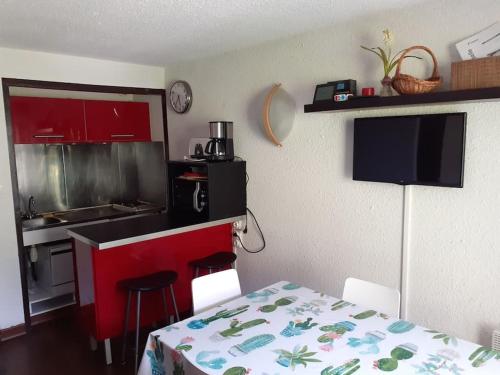 une cuisine avec une table et une cuisine avec des placards rouges dans l'établissement appart 6 personnes La Mongie, à Bagnères-de-Bigorre