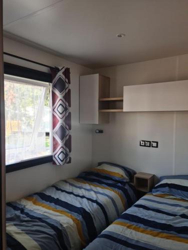 une chambre avec deux lits et une fenêtre dans l'établissement Mobil-home, à Lège-Cap-Ferret