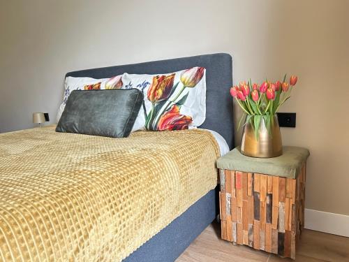 a bedroom with a bed with a vase of flowers at Lovely Spacious Apartment in Zandvoort