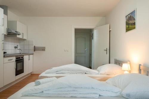 two beds in a white room with a kitchen at Sun Valley Apartments in Maishofen