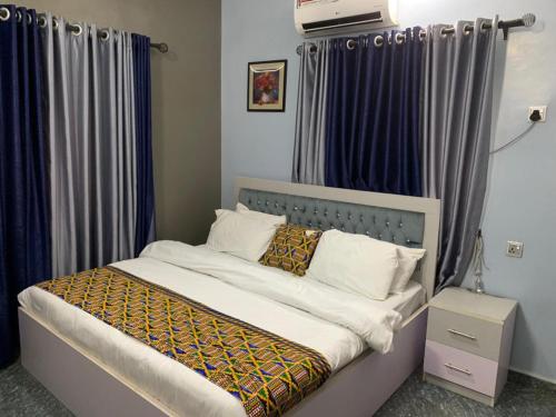 1 dormitorio con 1 cama con cortinas azules en Garden View Holiday Cottage en Abakaliki
