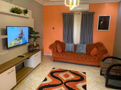a living room with a couch and a flat screen tv at Garden View Holiday Cottage in Abakaliki