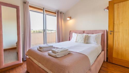 a bedroom with a bed with two towels on it at São Felix Seaview Retreat by LovelyStay in São Félix da Marinha