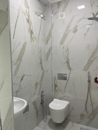 a white bathroom with a toilet and a sink at Hotel Aleksandrus Jardin in Durrës