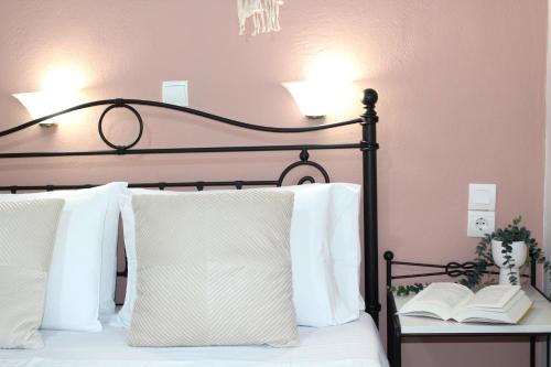 a bed with white pillows and a book on a table at Fissas Rooms in Sivota