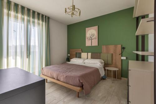 1 dormitorio con cama y pared verde en B&B Appia, en Brindisi