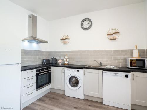 a kitchen with white cabinets and a washer and dryer at Kings Apartment 1 390 in Gowlaun
