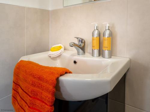 Una toalla naranja está sentada en el lavabo del baño. en Kings Apartment 1 390, en Gowlaun