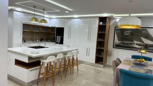 una cocina con armarios blancos y una isla con taburetes. en Luxury house with swimming pool en Ben Arous