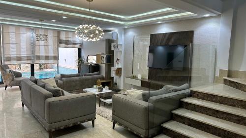 een woonkamer met banken en een flatscreen-tv bij Luxury house with swimming pool in Ben Arous