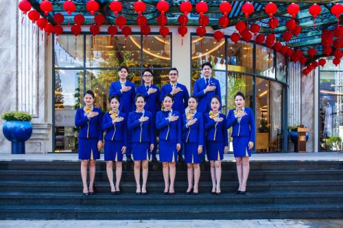 a group of people in blue uniforms standing in front of a building at SANDALS AQUILA HOTEL in Bao Loc