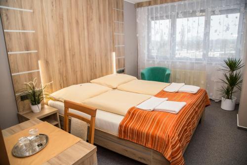 a bedroom with a bed and a table and a window at Hotel Panon in Hodonín