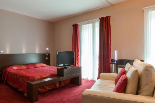 a hotel room with a bed and a couch at The Originals City, Hôtel Les Thermes de l'Avenue, Dax in Dax