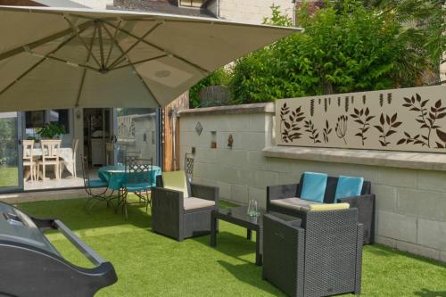patio z krzesłami i parasolem na trawie w obiekcie L'élégante w mieście Loches