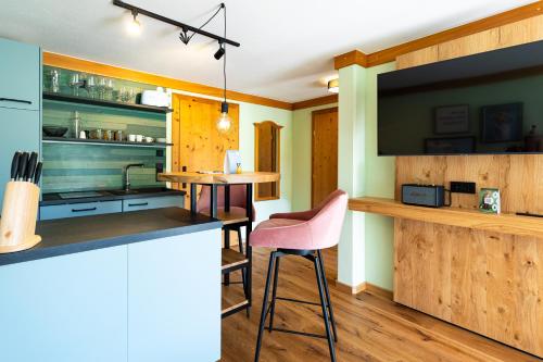 a kitchen with a counter and a bar with pink chairs at Wellness Aparthotel "Lechlife" incl Pool - 400m zum LIFT in Reutte
