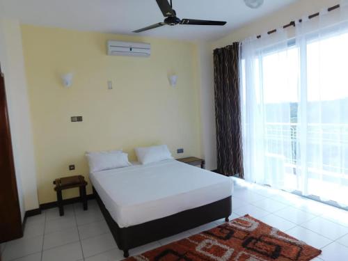 een slaapkamer met een wit bed en een groot raam bij Beachfront Paradise Apartment in Mombasa