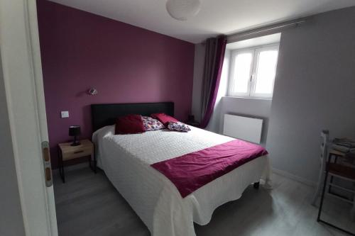 ein Schlafzimmer mit einem Bett mit lila Wänden und einem Fenster in der Unterkunft Gîte Le Chardet 