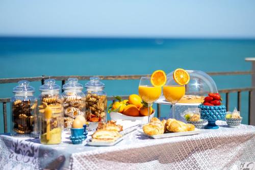 une table recouverte de verres de jus d'orange et de nourriture dans l'établissement Dolce Vita Rooms and Apartments, à Cefalù