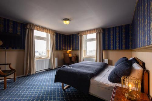 a hotel room with a bed and two windows at Milling Hotel Plaza in Odense