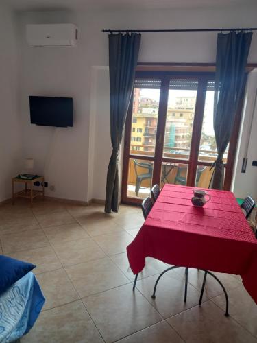 uma sala de estar com uma mesa vermelha e uma grande janela em FERRARO ALLOGGIO TURISTICO em Ladispoli