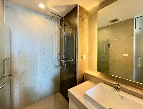 La salle de bains est pourvue d'une douche en verre et d'un lavabo. dans l'établissement The Astra one bedroom apartment, à Chiang Mai