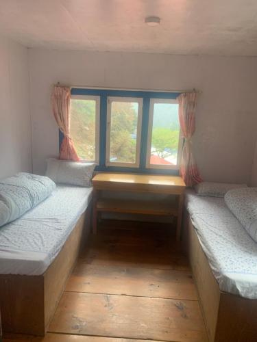 2 Betten in einem Zimmer mit Fenster in der Unterkunft Buddha Lodge in Chaunrikharka