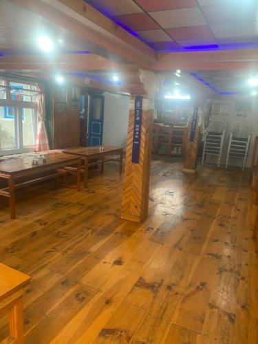 Buddha Lodge في Chaunrikharka: غرفة فيها طاولات وكراسي خشبية