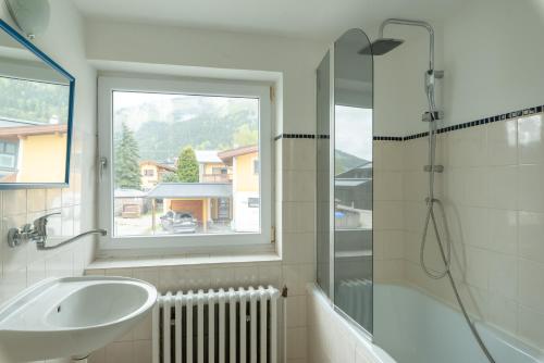 a bathroom with a sink and a shower with a window at Sun Valley Apartments in Maishofen