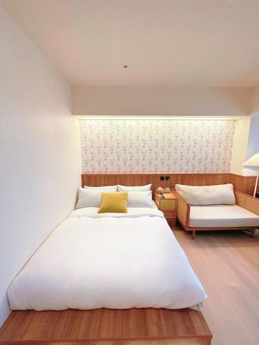 a bedroom with a large white bed and a couch at Cat Tail Pocket Inn in Taipei