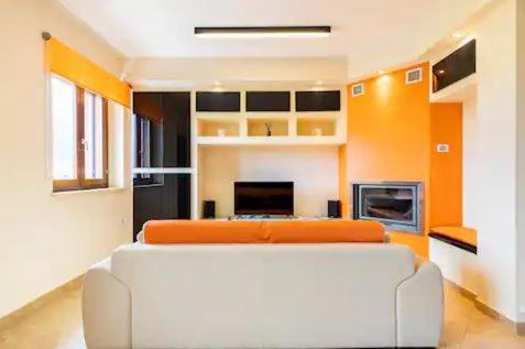 a living room with a white couch and an orange at Vacancuore, a casa di Giada in Bastia Umbra