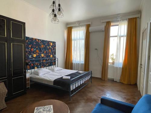 a bedroom with a bed and a couch and windows at Guest House Third Floor in Tbilisi City