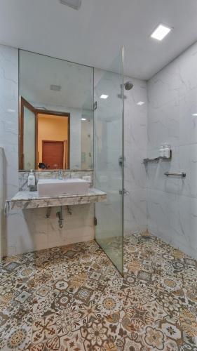 a bathroom with a sink and a glass shower at Elphinstone Hotel in Mumbai