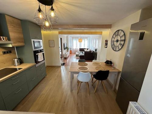 d'une cuisine et d'un salon avec une table et une horloge. dans l'établissement Magnifique appartement F3. 4 à 6 personnes, à Lutterbach