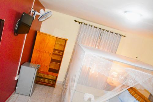 a room with a window with a curtain and a television at Lakeshore Bed and Breakfast in Entebbe