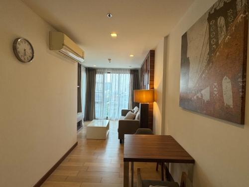 - un salon avec un canapé et un réveil sur le mur dans l'établissement The Astra one bedroom apartment, à Chiang Mai