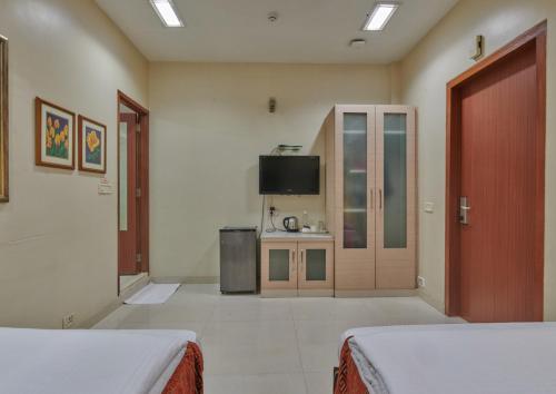 ムンバイにあるElphinstone Hotelのベッド2台とテレビが備わるホテルルームです。