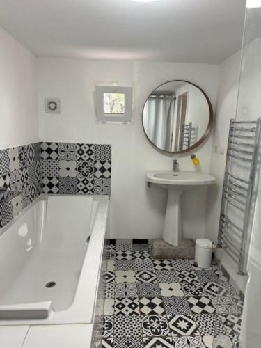 une salle de bain avec une baignoire, un lavabo et un miroir dans l'établissement Appartement dans résidence calme dans les Monts du Lyonnais, à Soucieu-en-Jarrest