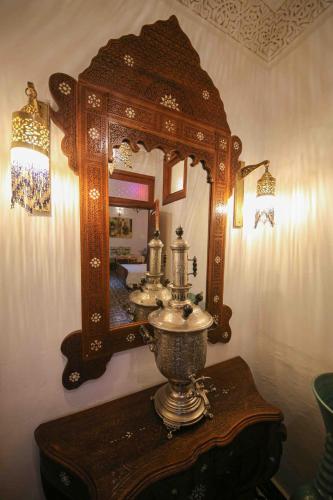 a mirror on a wall next to a table with a sink at Dar Dalila Fes in Fès