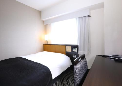 a hotel room with a bed and a desk and a window at APA Hotel Ueno Ekikita in Tokyo