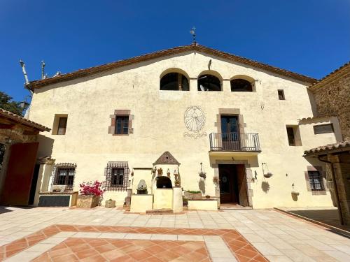 a large white building with a clock on it at Masia Can Viver - Olive oil tourism B&B in Bigues i Riells