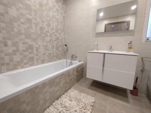 un bagno con vasca bianca, lavandino e vasca tubermott di San Pawl Lodge a San Pawl il-Baħar