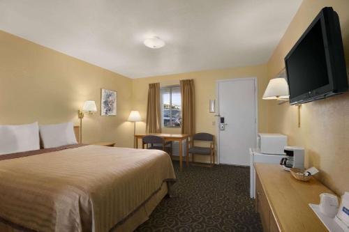 Travelodge by Wyndham Wenatchee في ويناتشي: غرفة فندقية بسرير وتلفزيون بشاشة مسطحة