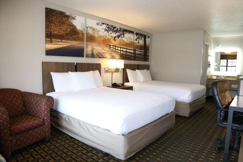 a hotel room with two beds and a chair at Days Inn by Wyndham Monroe in Monroe
