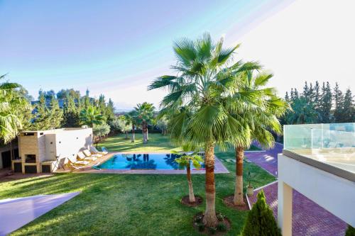 an image of a villa with a swimming pool and palm trees at *Villa de luxe à Marrakech, vue sur les montagnes* in Marrakech