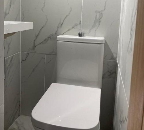 a white toilet in a bathroom with marble walls at Peaceful Home Berrylands Surbiton Surrey UK - Free Parkings in Surbiton