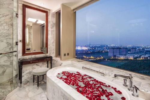 a bathroom with a tub filled with red roses at Ramada Plaza Qiandeng Kunshan in Kunshan