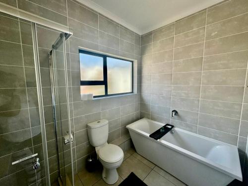 baño con aseo, bañera y ventana en Ballito Hills 2 bedroom apartment 1272, en Ballito