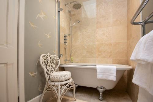 a bathroom with a tub and a chair and a shower at Lane Cottage in Coldstream